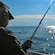 A man holding a fishing pole near the ocean
